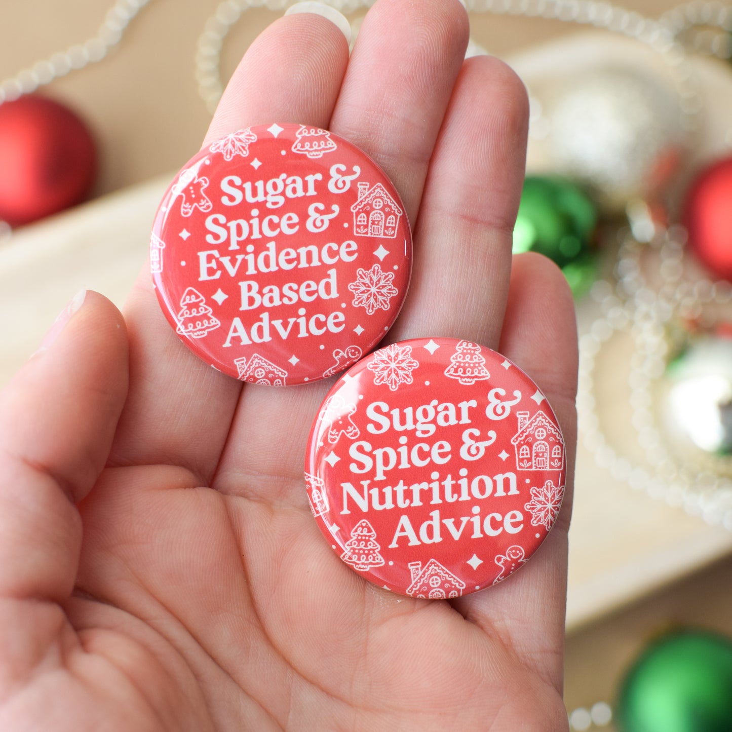 Two red buttons with white text held in a hand, surrounded by festive decorations.