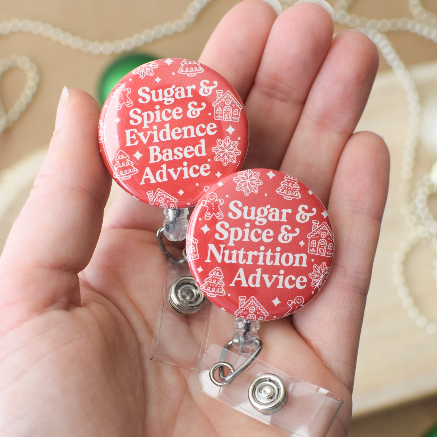 Two red badge reels with text held in a hand against a beige background
