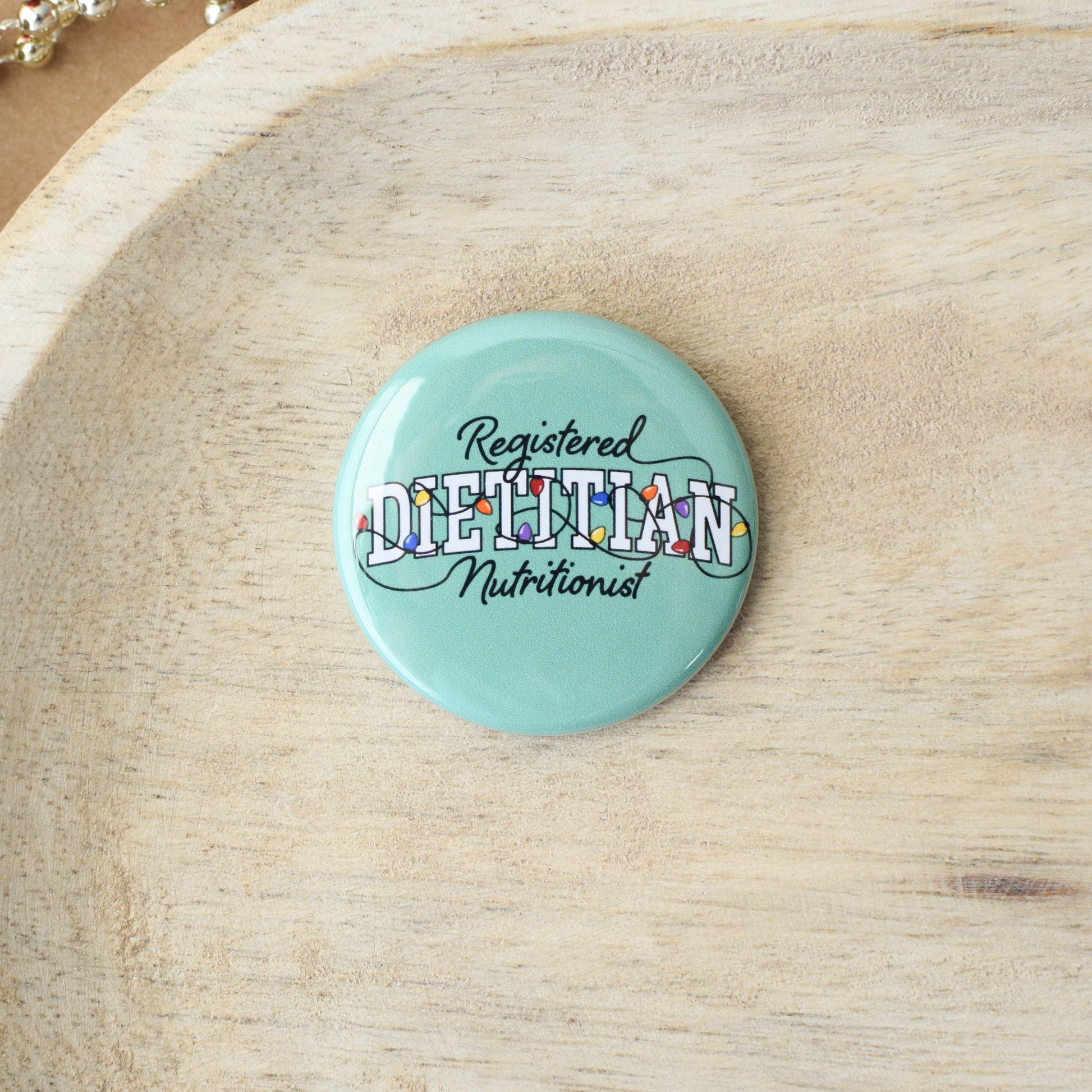 Button badge with 'Registered Dietitian Nutritionist' text on a light green-blue background, placed on a wooden surface.