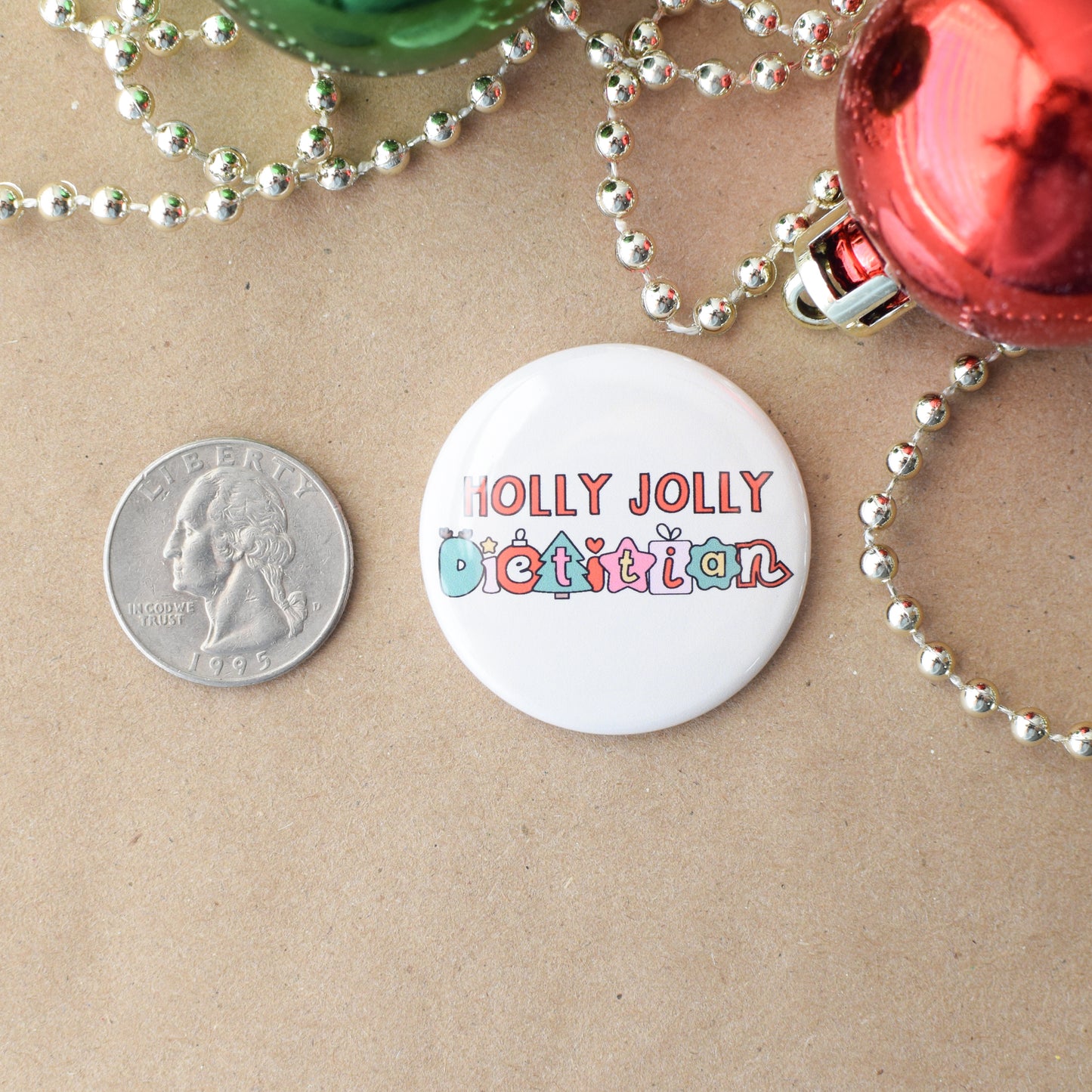 Button badge with 'Holly Jolly Dietitian' text on a beige background with Christmas decorations.