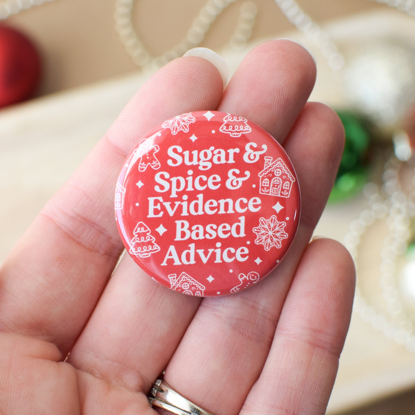 Red button with white text held in a hand, featuring decorative elements.