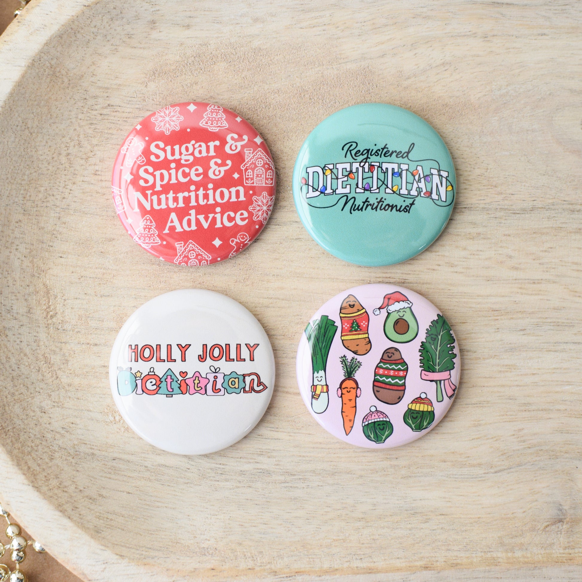 Four colorful buttons with holiday nutrition and dietitian themed text on a wooden surface
