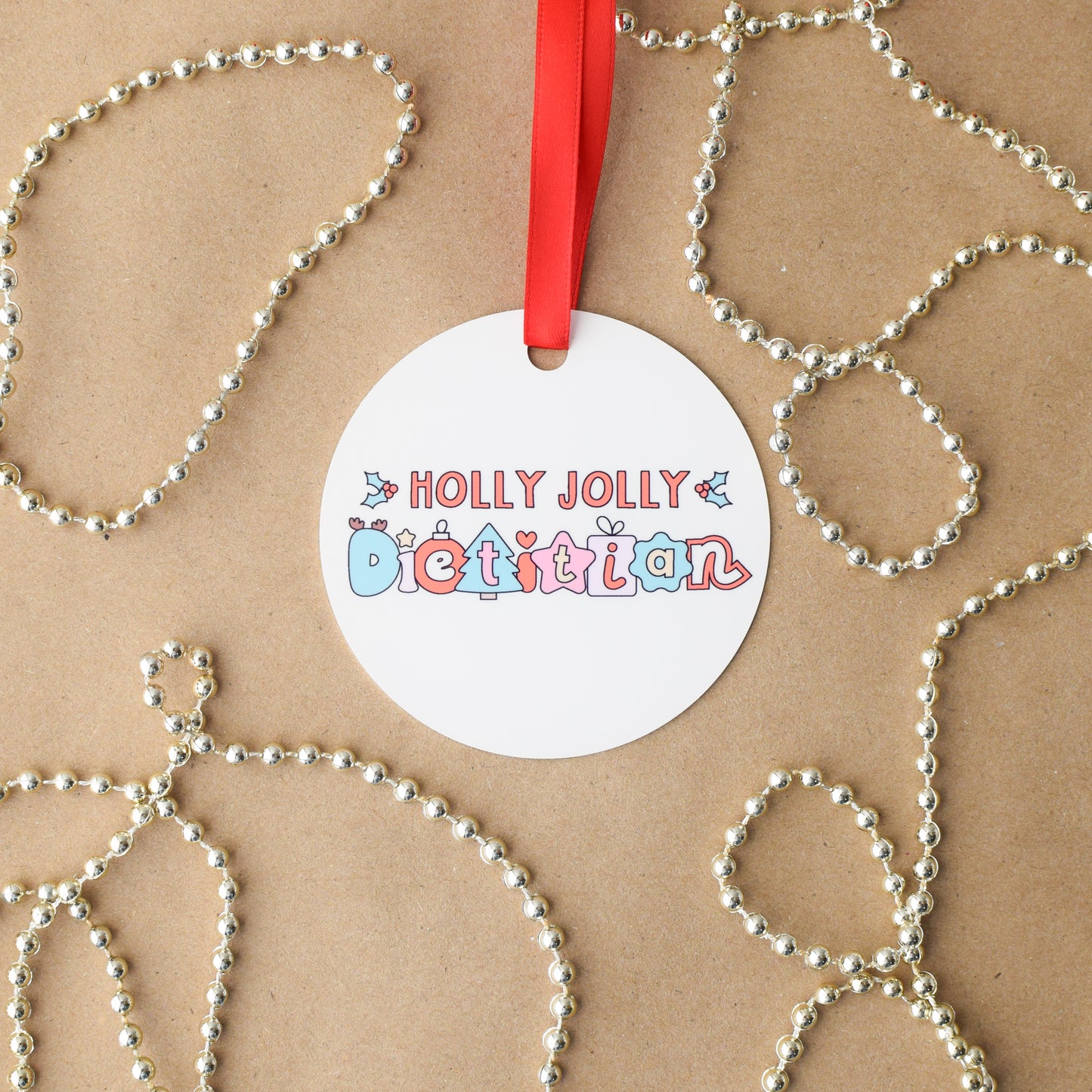 Round off-white ornament with 'Holly Jolly Dietitian' text on a brown background with decorative elements.