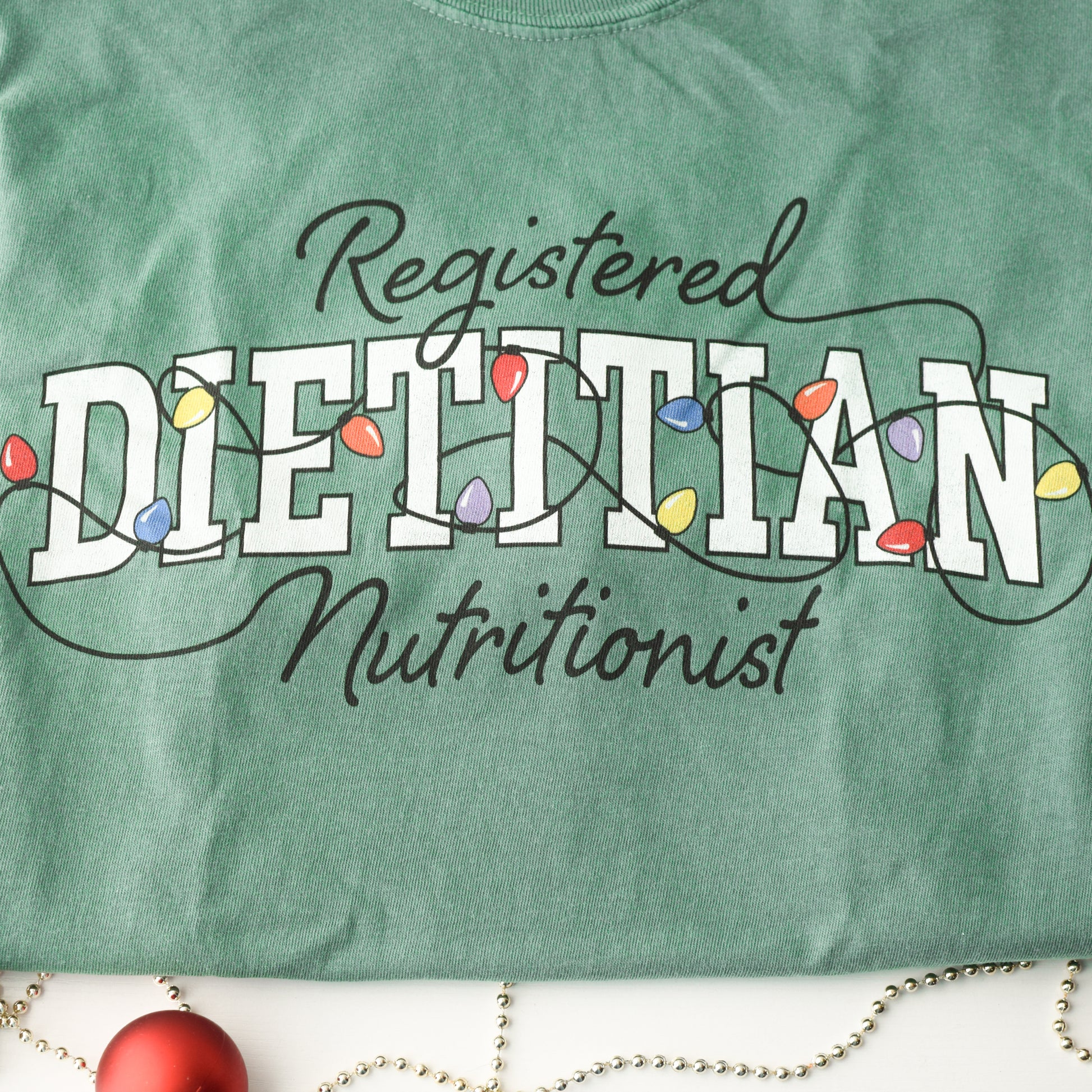 Close up of green tshirt with Registered Dietitian Nutrition text tangled in Christmas lights