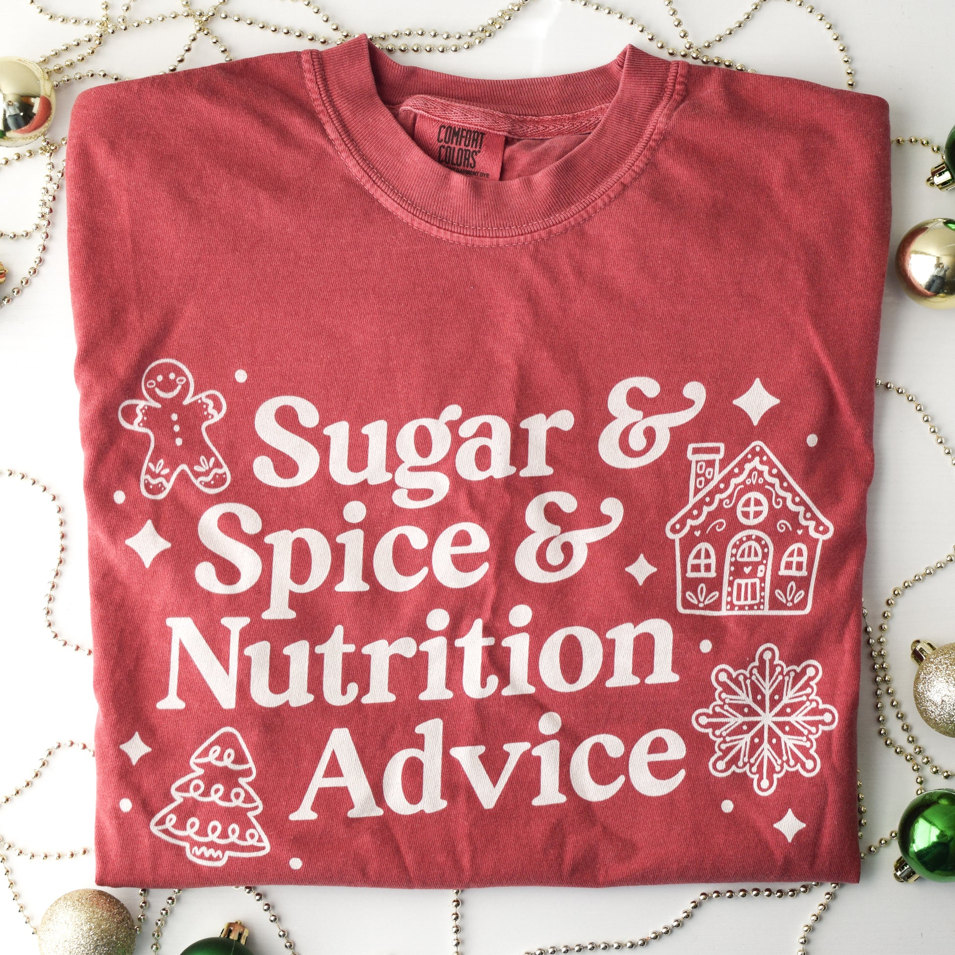 Red t-shirt with white text 'Sugar & Spice & Nutrition Advice' and white gingerbread cookie graphics on a decorative background