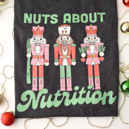 Charcoal t-shirt with nutcracker design and 'Nuts About Nutrition' text, surrounded by Christmas decorations.