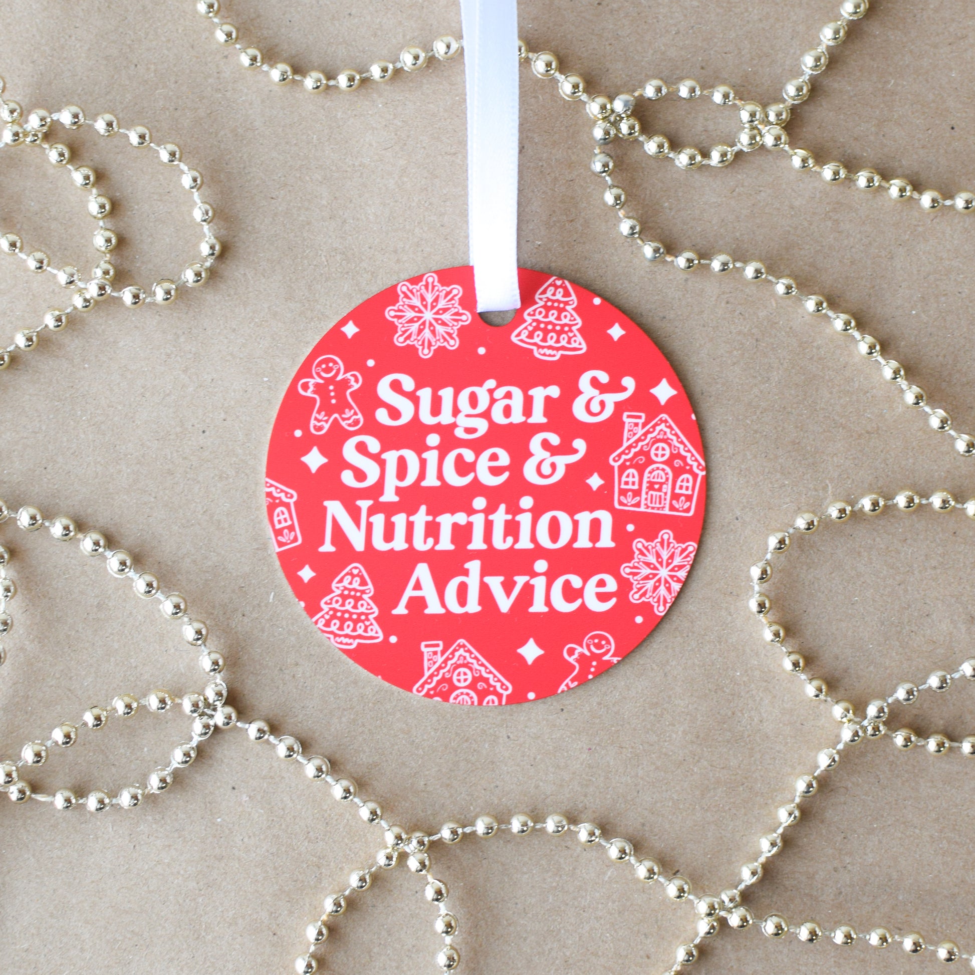 Red circular ornament with 'Sugar & Spice & Nutrition Advice' text on a textured background with decorative strings.