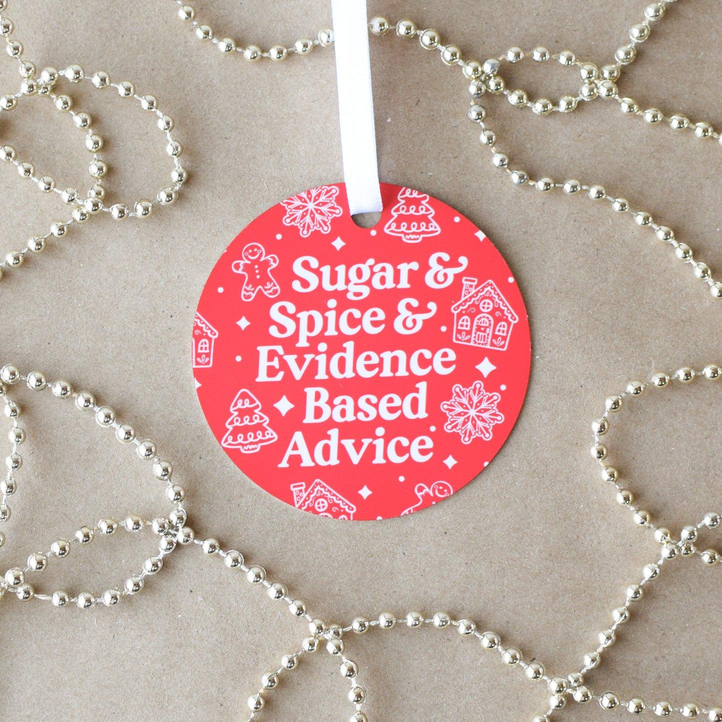 Red circular ornament with text 'Sugar & Spice & Evidence Based Advice' on a beige background with gold beads.