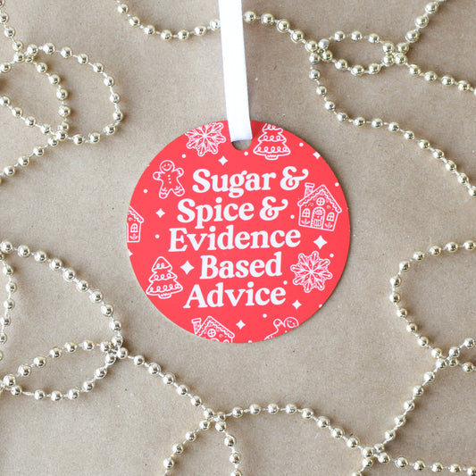 Red circular ornament with text 'Sugar & Spice & Evidence Based Advice' on a beige background with gold beads.