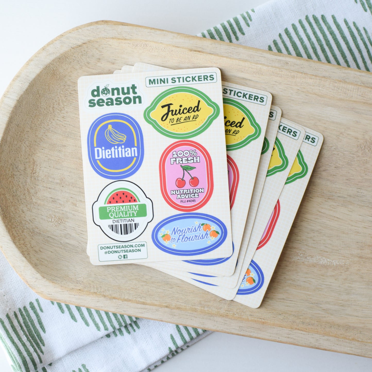 Set of colorful stickers on a wooden tray with a white and green patterned cloth underneath.