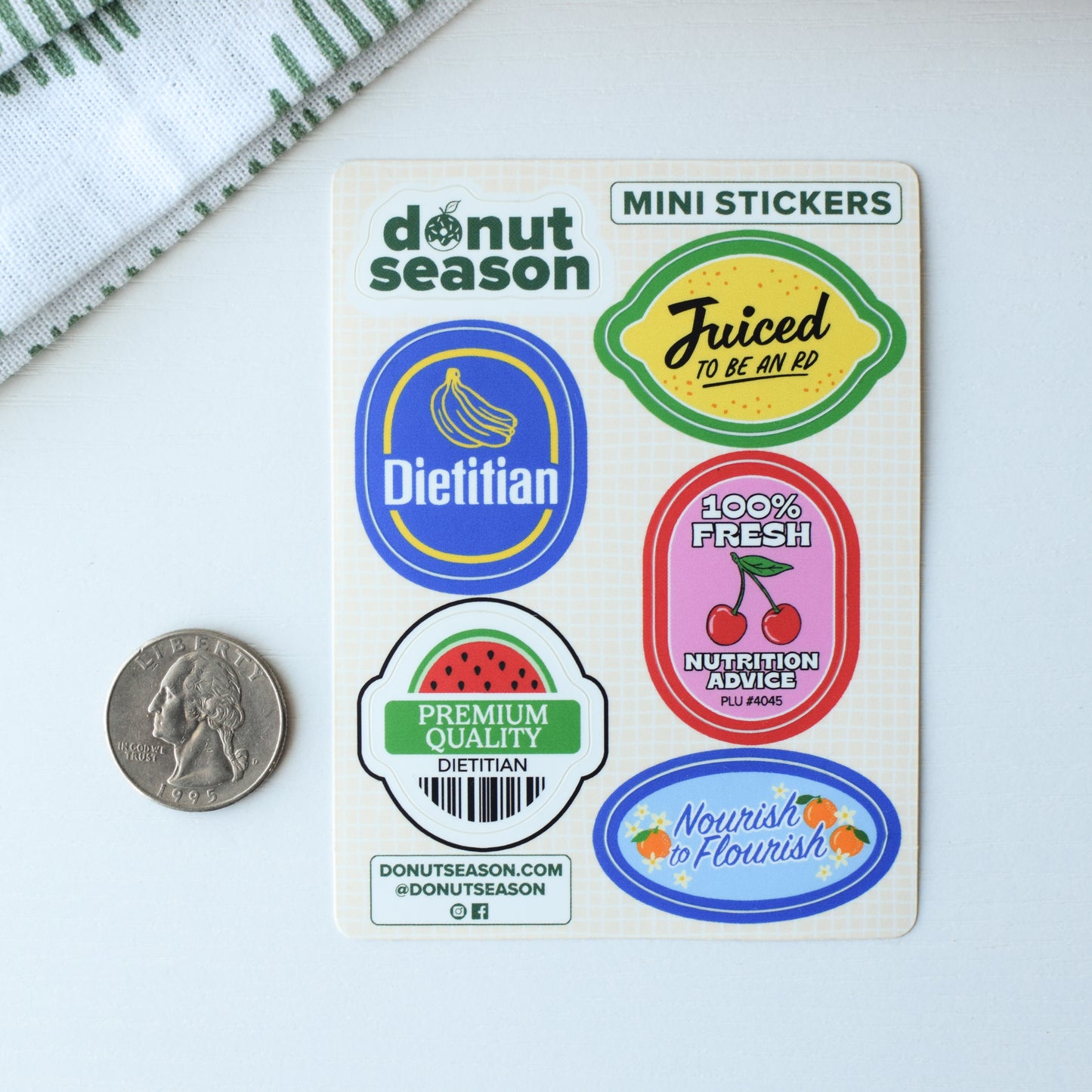 Set of mini stickers from 'Donut Season' on a white surface with a coin for scale.